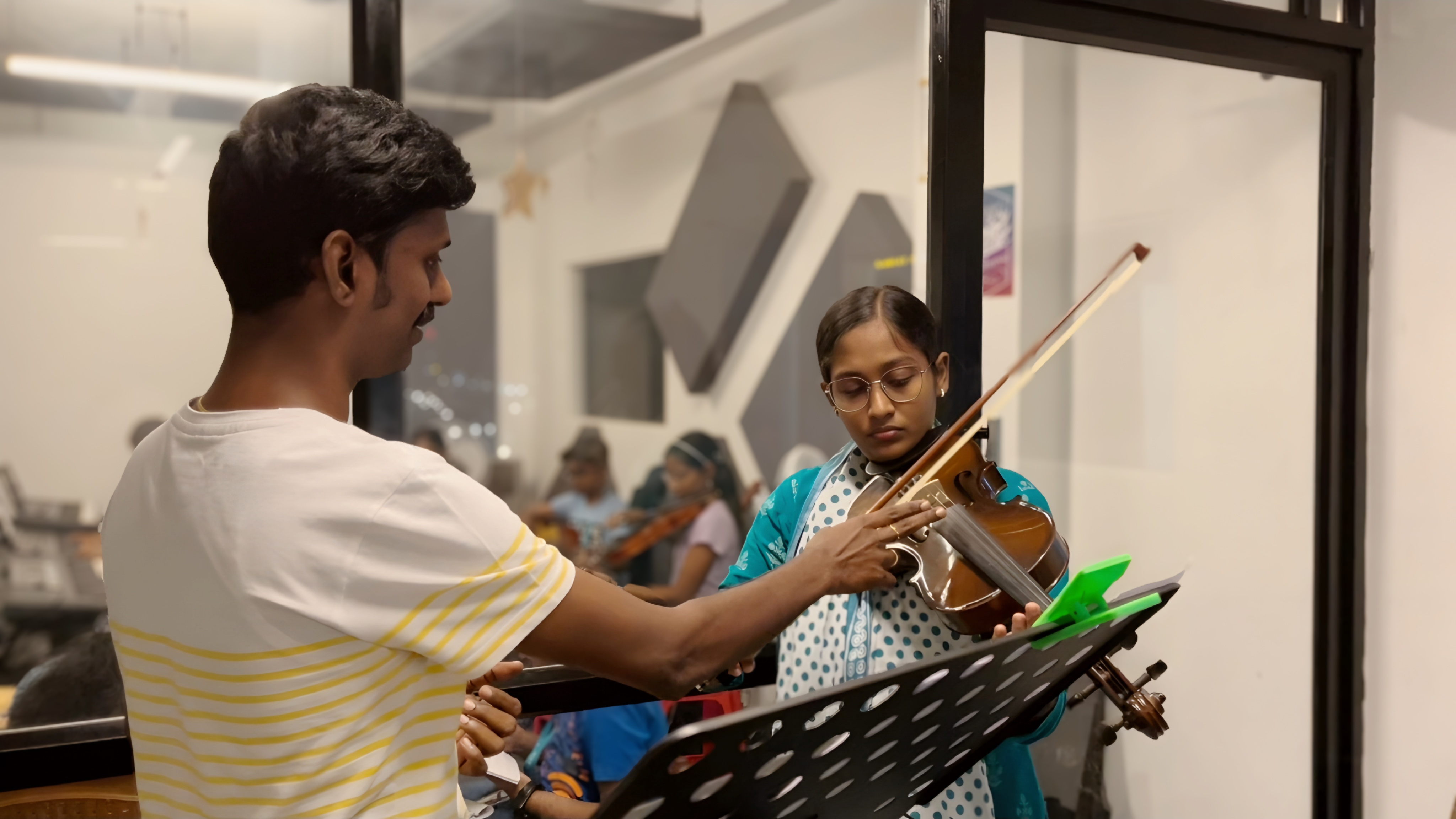 A violin duo perform alongside each other, reading sheet music